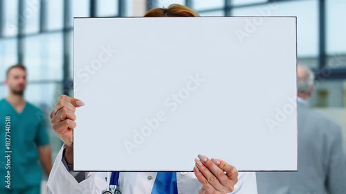 Female doctor's hands holding a blank poster in a hospital