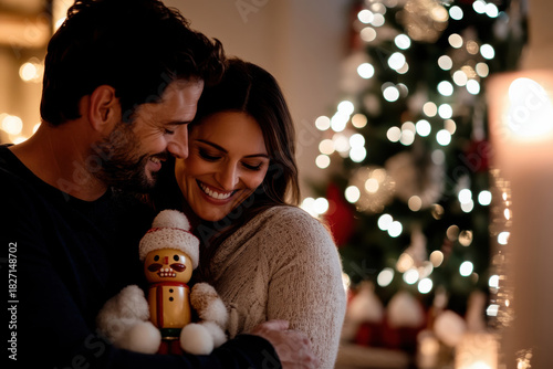 A couple sharing a joyful moment, embracing each other while holding a festive decoration, symbolizing love and happiness during the Christmas holiday season.