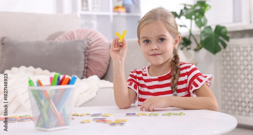 Fototapeta premium Little girl learning alphabet with letters at white table indoors