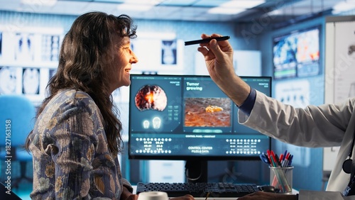 Fotografie Male medic doing a neurological consultation with a pen light to assess a patient cognition, pupil response and reflexes, checking for signs of concussion or brain injury