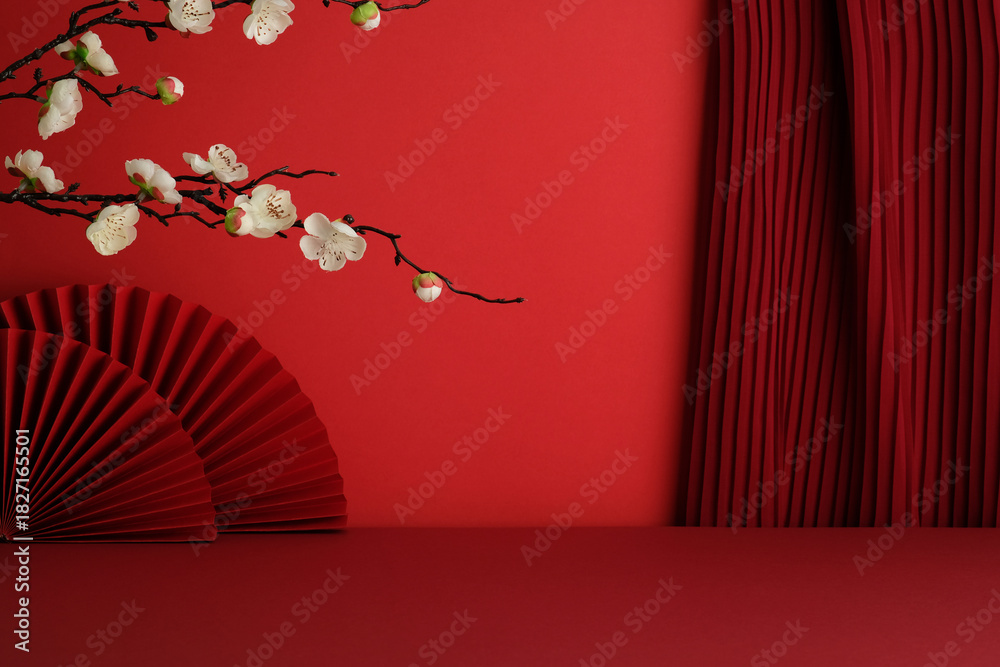 Obraz premium White blossoms over a red fan with deep red pleated curtains and red stage.