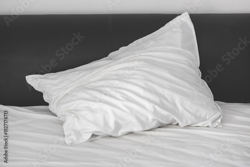 A crumpled white pillow lies on the bed after sleeping