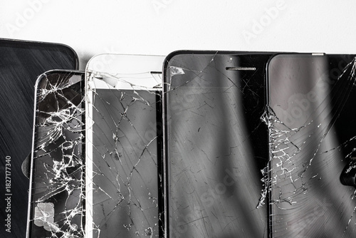 A pile of broken phones lies on a white background, many broken phones.