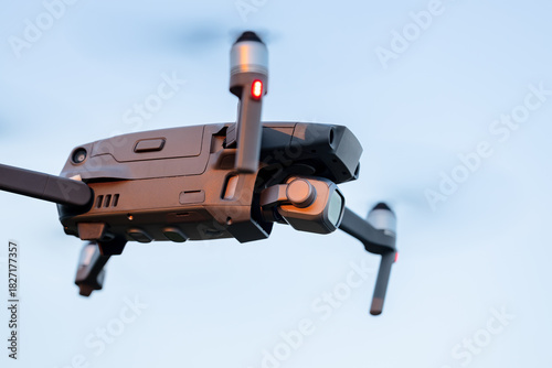 Drone hovering in the sky, unmanned aerial vehicle against blue sky