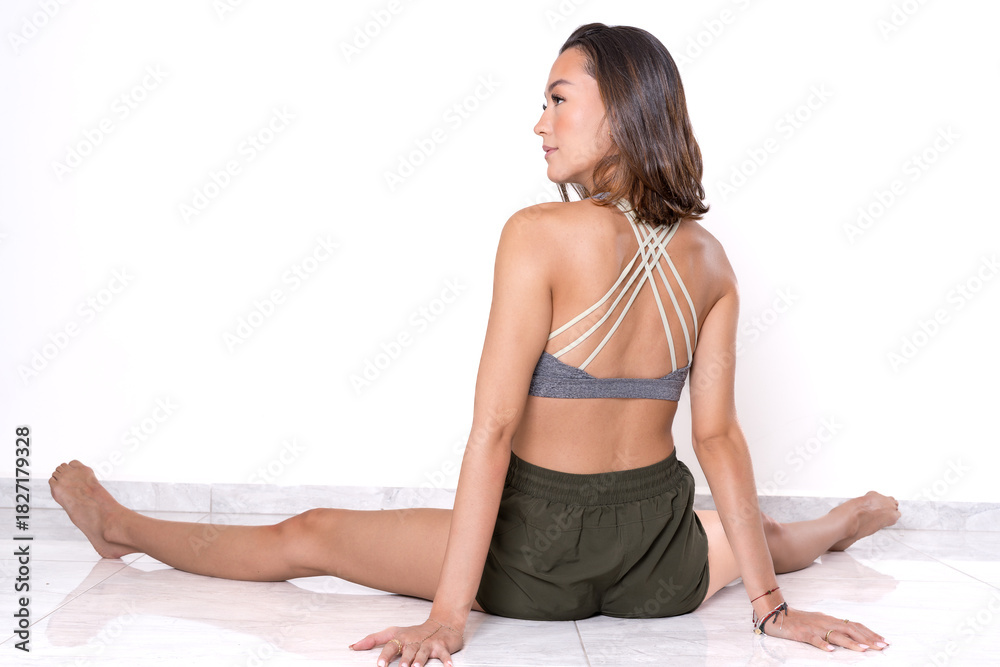 Fototapeta premium Rear view of woman doing seated split stretch.