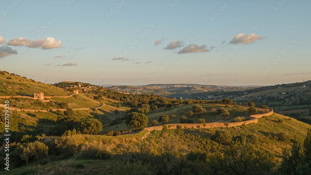 Obraz premium Lush green hills and farmland under a partly cloudy sky during the daytime.