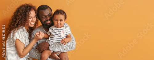 Happy African-American parents with cute baby on color background