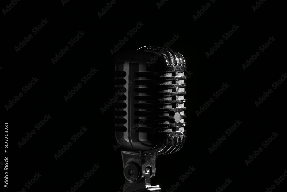 Fototapeta premium Vintage microphone on a stand classic audio equipment for broadcasting music and public speaking isolated on a dark background