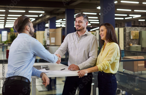 Friendly furniture shop consultant exchanges handshakes with customers. Happy couple shake hands with salesman at home renovation store thanking for help with on hire purchase installment payment plan