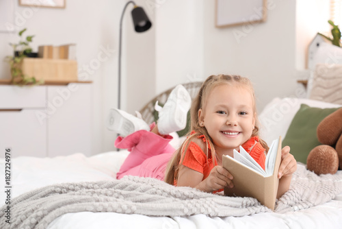 Cute little girl reading bo...