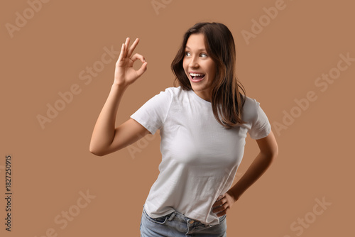 Young woman showing OK on brown background