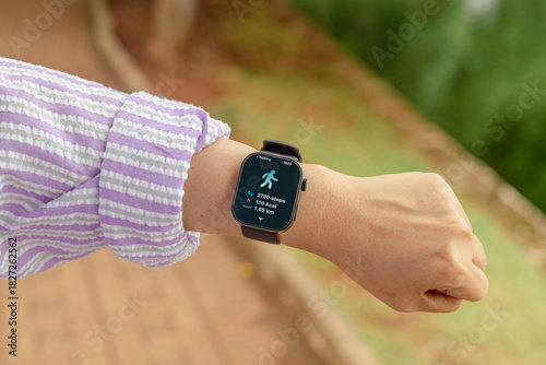 A woman counting her steps using her smart watch. Outdoors.