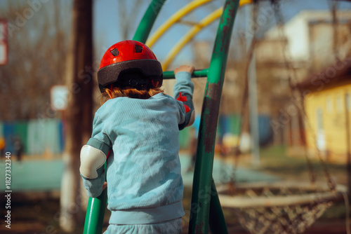 Foto Child with Protective Equipment Climbs at the Playground