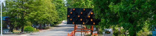 Arrow board used to direct traffic around temporary lane closure, move over lighted road sign with arrows, suburban traffic control
