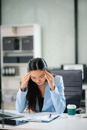 Frustrated young businesswoman working on a laptop computer sitting at his working place in office