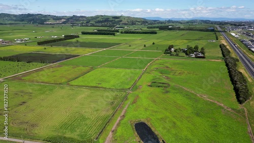 Aerial view of Papamoa countryside with bright fields, scattered farm buildings and wide open rural space. New Zealand.