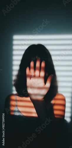 Woman hiding face with hand, shadows from blinds.