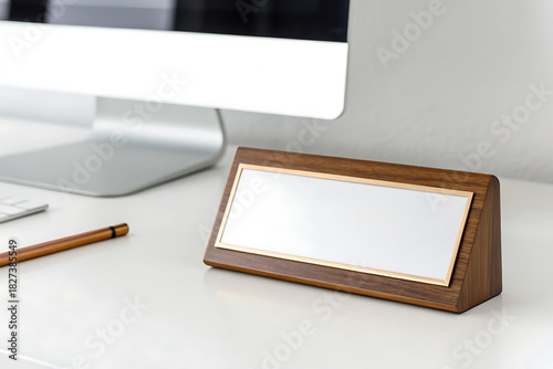 Blank wooden name plate on desk next to computer and pencil