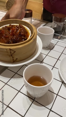 4k video footage of A chinese restaurant male waiter brought the baozi dumplings dimsum and chicken feet with charsiu in a wooden bamboo steamer.