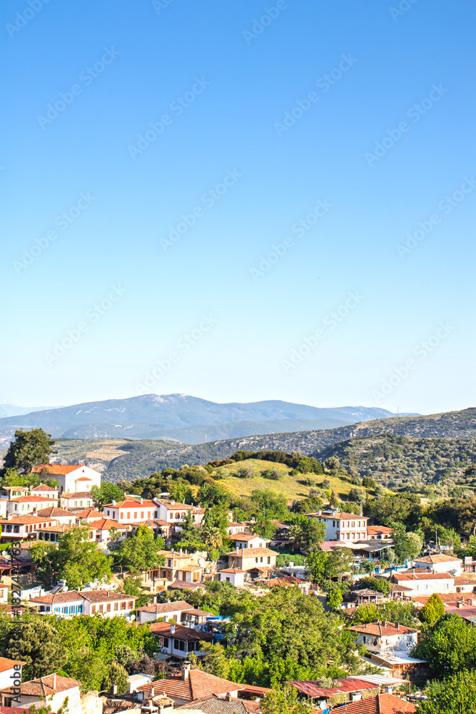 Fototapeta premium Sirince village on the background of blue sky and green hills. Popular tourist destination, old Greek village. Sirince, Izmir. 