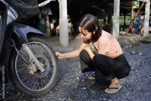 Woman pumping air into a motorcycle tire.