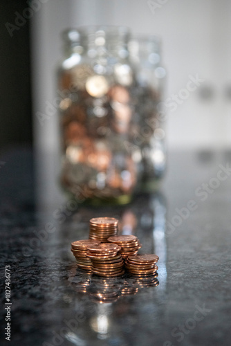 Obraz na plátně Vertical image of coins in front of a jar of pennies