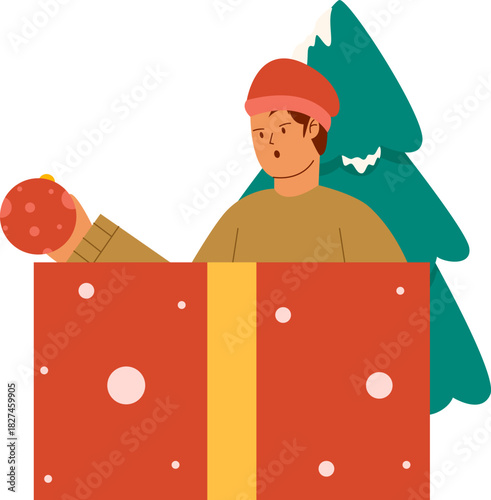 Man opens a giant present box while holding a Christmas ornament near a tree.