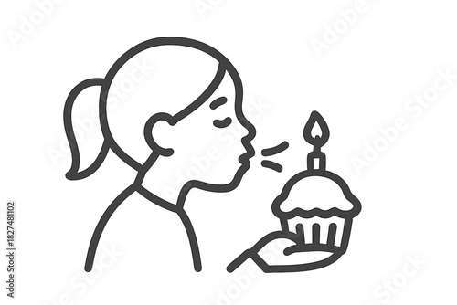 Young person in profile blowing out a lit candle on a small birthday cupcake during a celebration