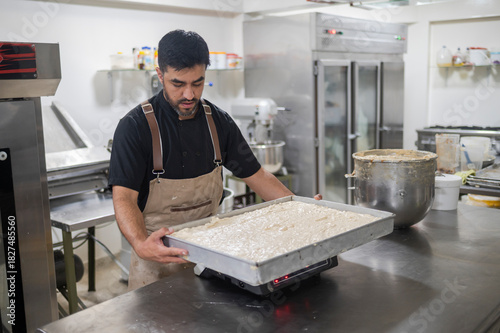 Baker weighing dough in a commercial bakery kitchen