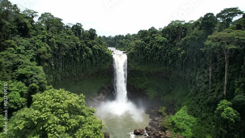Beautiful tropical waterfall cascade flows through a lush green rainforest park in Thailand with natural stone stream and mountain landscape beauty