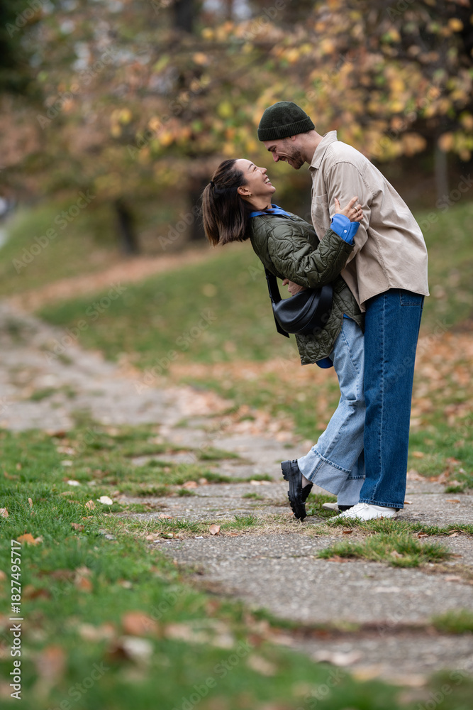 Fototapeta premium Happy couple embracing, laughing in autumn park