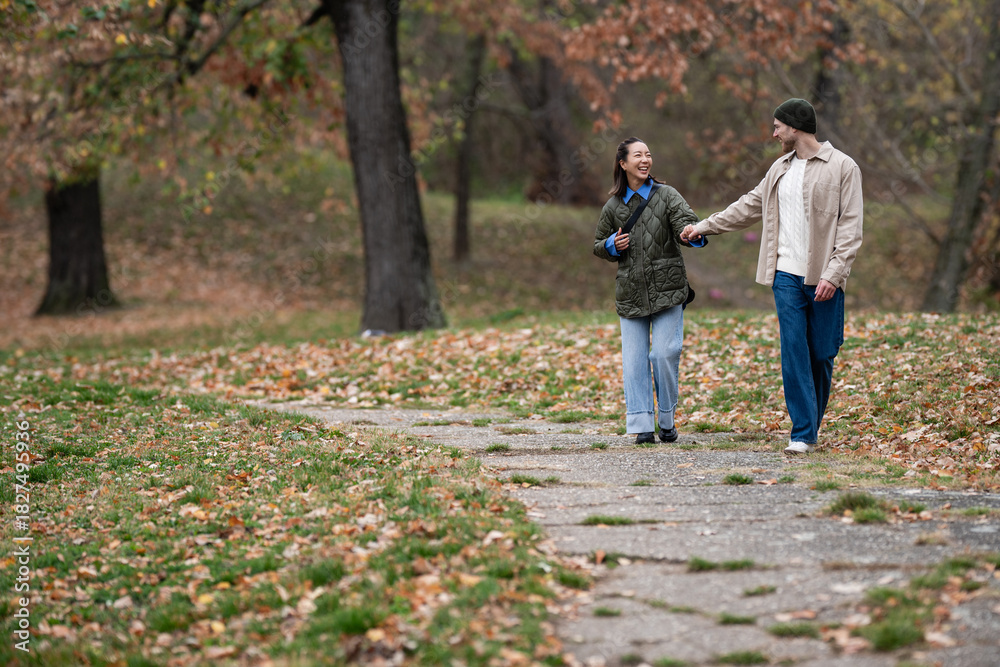 Fototapeta premium Couple walking hand in hand in autumn park