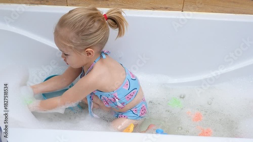 Little child girl in a swimsuit bathing in a bubble bath