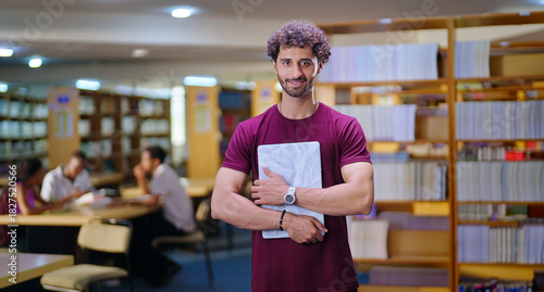 Indian young adult gen z man student standing proud hold new laptop look camera indoor library happy smiling boy guy staring cam do casual pose enjoy new joyful day time inside college