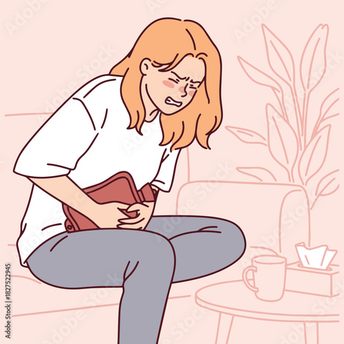 Girl sits bent over on the couch hugging a hot water bottle to relieve strong abdominal pain. Woman struggles with endometriosis symptoms and tries to warm her belly.