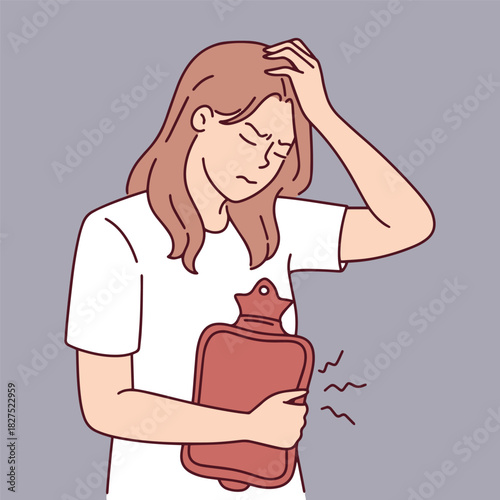 Unhappy girl stands clutching a hot water bottle to her belly due to severe menstrual cramps. Young woman experiencing abdominal pain and discomfort during period.