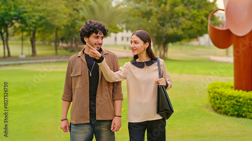 Indian young adult gen z smart male female wear bag walk talk casual gossip share new day plan spend break time place. Happy teen girl cool boy man pupil guy speak funny joke have fun joy garden park