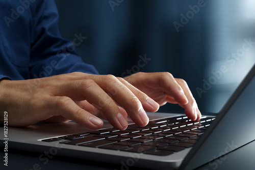 Businessperson using laptop computer at desk in office. Closeup of hands and keyboard. Business technologies.