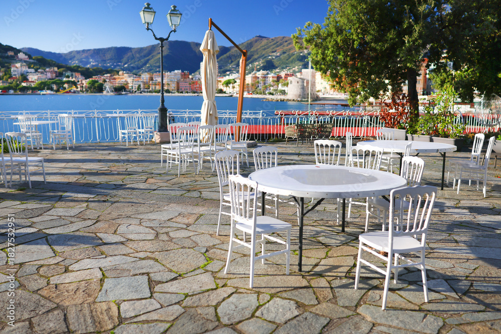 Fototapeta premium White furniture on terrace by sea on sunny day. Tourism and recreation, Europe. Nature and architecture of Italy. Design backdrop.