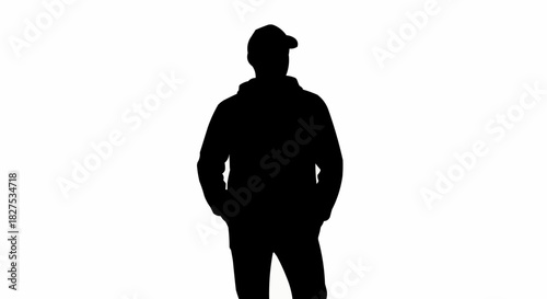 Silhouette of a man standing with hands in pockets wearing a cap.