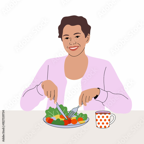 A cheerful woman sits at a table happily cutting a fresh salad filled with vibrant vegetables, showcasing a healthy and delightful meal. The simple joys of dining are evident.