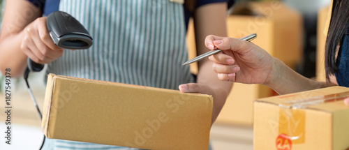 E-commerce. Woman checking package details while scanning in a modern workspace.