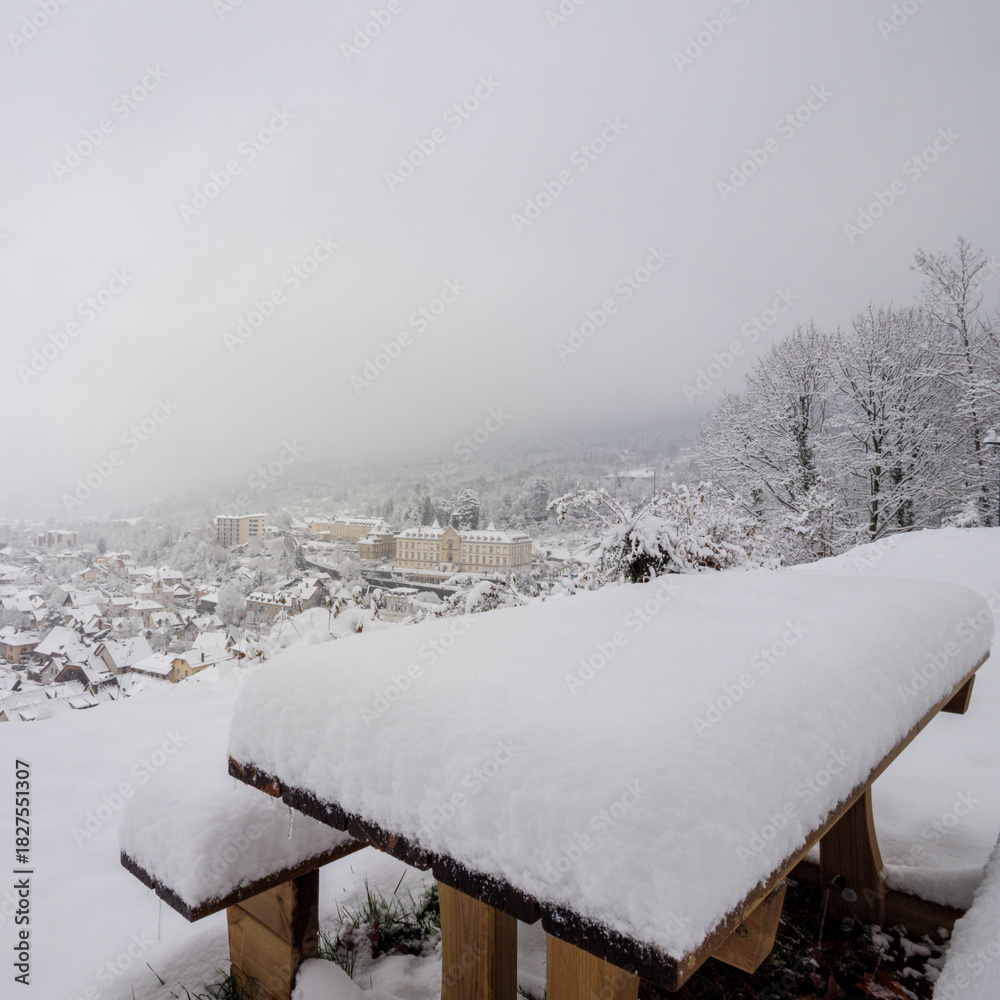 Fototapeta premium Snowy picnic table overlooking the peaceful town of Saint-Laurent-du-Pont.