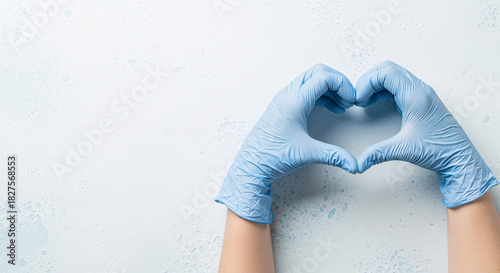 Hands in blue surgical gloves making heart shape on white background with copy space