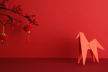 Happy Chinse New Year 2026 concept. Red origami horse and two red hanging lanterns against a vibrant red backdrop.