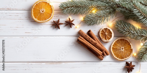 Festive Christmas flat lay with fir branches, dried orange slices, cinnamon sticks, star anise, and warm lights on a white wooden background. Cozy and natural holiday decoration.