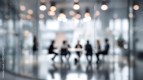 Blurred image of business people silhouettes sitting around table meeting in a modern glass-walled office space with warm bokeh lights creating atmosphere of collaboration and professionalism