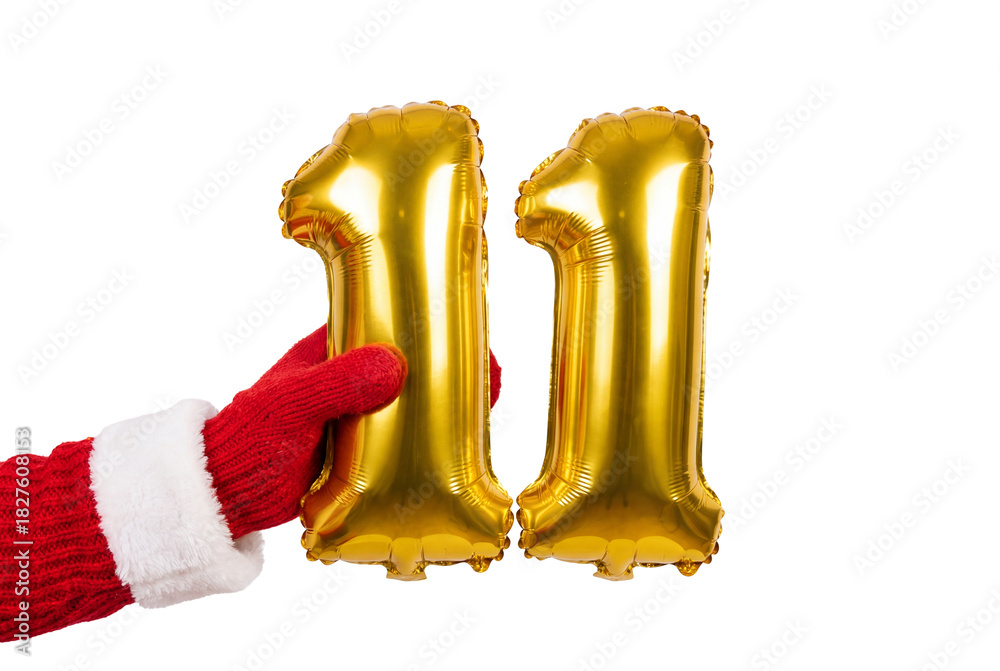 Fototapeta premium Hand in red winter glove holding gold number eleven balloons on white background, festive party decor for birthday anniversary and holiday countdown celebration
