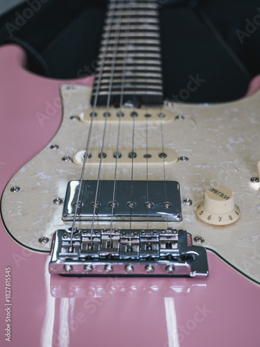 Close-up of a pink electric guitar with pearl pickguard and chrome hardware. This image showcases the details of a stylish electric guitar, perfect for music enthusiasts and designers