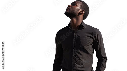 Man in black shirt looking up against a white background during bright daylight.